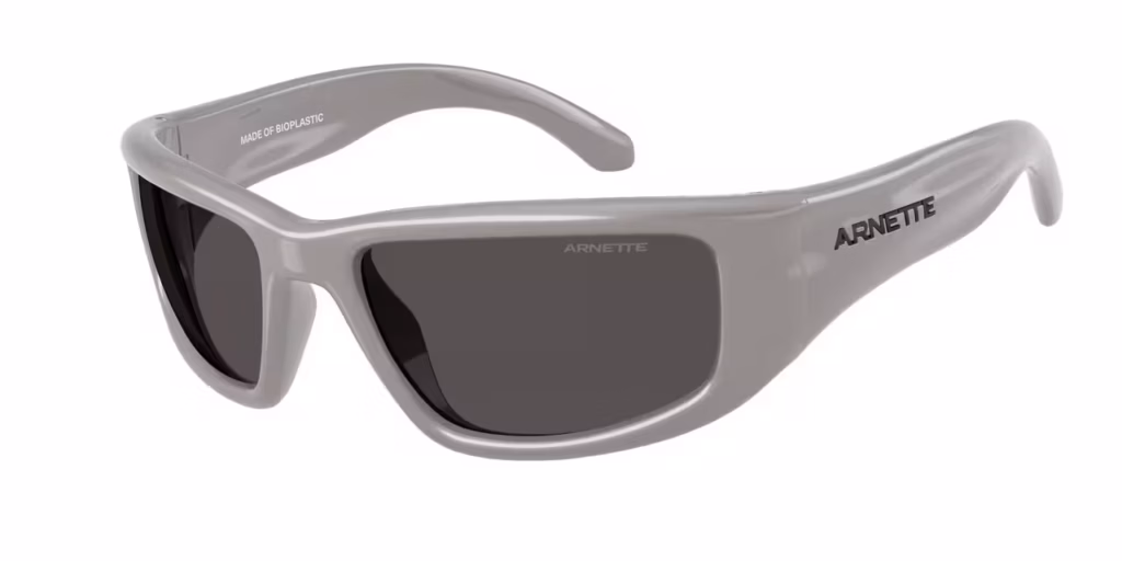 A light grey, wrap-around style sunglass frame with dark grey lenses, showing the logo on the side arm.