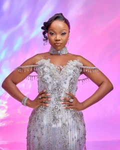 Zanele Potelwa Durban July 2025 in shimmering silver gown, posing confidently in a vibrant studio shoot.