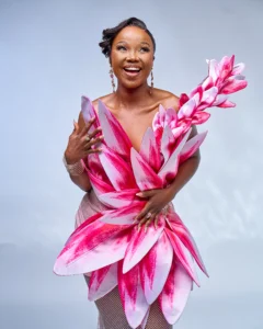 Zanele Potelwa Durban July 2025 in vibrant pink floral dress, posing confidently in a studio shoot.