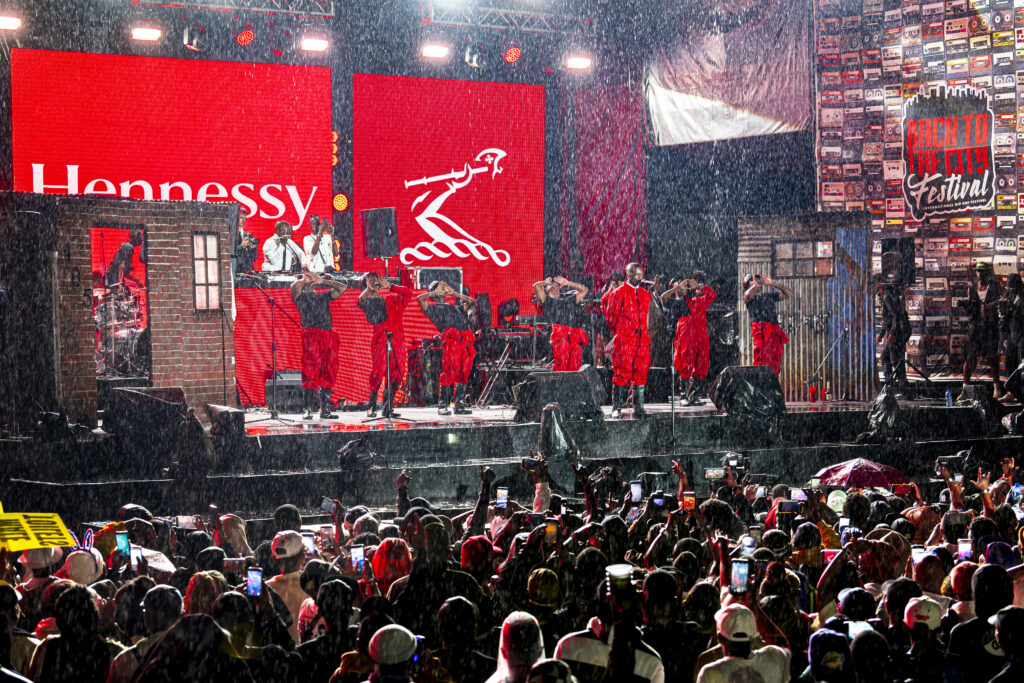 A wide shot of the main stage during a rainy performance at the Back to the City Festival, clearly showing the festival branding.