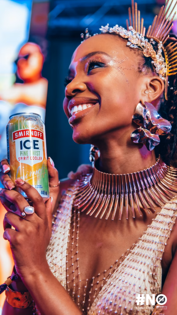 Close-up of a stylishly dressed woman in gold accessories smiling, holding a can of Smirnoff ICE Pine Twist at the Sun City event.