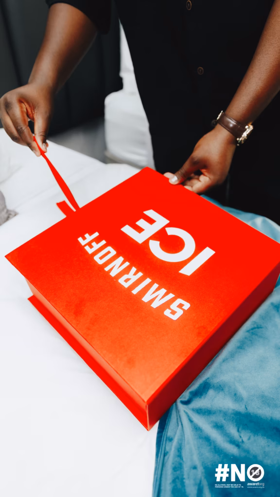 Close-up of hands opening a red branded SMIRNOFF ICE box, showcasing the curated welcome package for guests at the takeover.