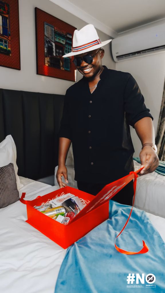 A smiling guest/influencer opening a red branded gift box on a bed, part of the welcoming experience at the Smirnoff ICE Fon City weekend.