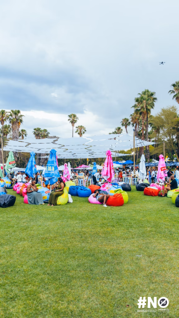 Wide shot of attendees relaxing on colourful beanbags under shade sails and palm trees during the Smirnoff ICE Fon City day club takeover.