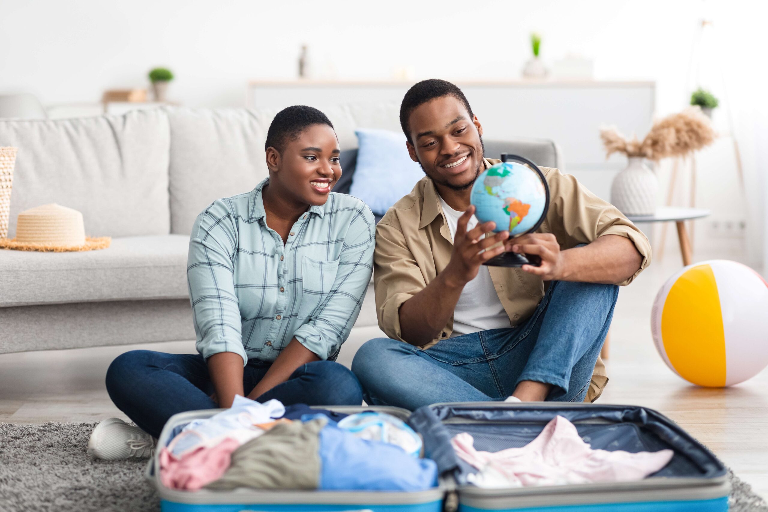 couple packing a suitcase and looking at globe